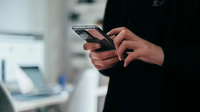 Hands holding a smartphone in a bedroom