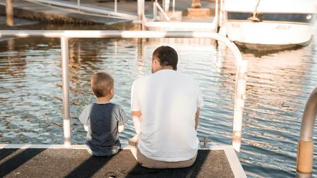 A father and his son sitting together on a dock